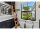 Laundry room with ladder, navy cabinets, and a bright window overlooking the yard at 6018 Abbey Oaks Dr, Lakeland, FL 33811