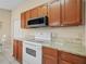 Kitchen with wooden cabinets, granite counters, and white appliances at 6337 Egret Dr, Lakeland, FL 33809