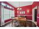 Bright dining room featuring a wooden table set under an elegant chandelier, complemented by red walls and dark hardwood floors at 6846 Ashbury Dr, Lakeland, FL 33809