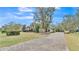 Long brick paver driveway leading to a home with stone accents, mature trees, and meticulous landscaping at 6942 Indian Creek Park Dr, Lakeland, FL 33813