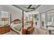 Tranquil main bedroom with a four-poster bed, tray ceiling, and French doors leading to a private outdoor area at 6942 Indian Creek Park Dr, Lakeland, FL 33813