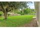 Large grassy backyard featuring mature landscaping and a privacy fence, perfect for outdoor activities at 7444 Hunters Greene Cir, Lakeland, FL 33810