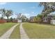 View of the backyard and long driveway leading to a detached garage with brick exterior at 1539 E Fern Rd, Lakeland, FL 33801