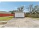 Detached two car garage with white doors and brick accents with long concrete driveway and red fencing at 1539 E Fern Rd, Lakeland, FL 33801