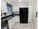 Bright kitchen offering white cabinets, black countertops and a stainless steel refrigerator at 327 Corona Del Mar St, Lakeland, FL 33809