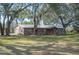 Rustic home featuring wood siding, a metal roof, inviting front porch, and a spacious, tree-shaded yard at 4075 Davis Rd, Mulberry, FL 33860