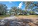 Long shot of a rustic home with a long driveway, large yard, and shaded by mature oak trees at 4075 Davis Rd, Mulberry, FL 33860