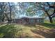 Charming wood home with a metal roof, red door, and beautiful mature trees in the front yard at 4075 Davis Rd, Mulberry, FL 33860