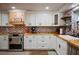 Updated kitchen featuring white cabinets, brick accents, butcher block countertops, and modern appliances at 4075 Davis Rd, Mulberry, FL 33860