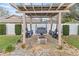 Backyard stone fire pit sitting area under pergola with swing chairs, lush landscaping, perfect for entertaining at 4624 Kings Point Ct, Lakeland, FL 33813