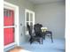 Charming front porch featuring a red front door, a small seating area, and white trim at 477 Kensington View Dr, Winter Haven, FL 33880