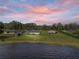 Waterfront homes with a metal roof, set against a colorful sunset sky and tranquil lake backdrop at 5418 Cooper Ln, Fort Meade, FL 33841