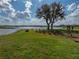 Expansive backyard featuring mature trees and manicured lawn stretching to a serene lake with a wooden dock at 5418 Cooper Ln, Fort Meade, FL 33841