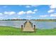 A picturesque view from a wooden dock extending into a serene lake, under a bright, cloud-filled sky at 5418 Cooper Ln, Fort Meade, FL 33841