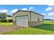 Large metal detached garage with a wide door and tidy landscaping on a sunny day near the lake at 5418 Cooper Ln, Fort Meade, FL 33841