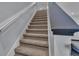 Carpeted staircase with a gray handrail and white walls at 5806 Valentino Way, Lakeland, FL 33812