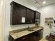 Functional kitchen features dark wood cabinetry, granite countertops, a stainless steel microwave, and shelving for storage at 585 Meandering Way, Polk City, FL 33868