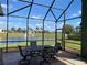 Screened-in patio with comfortable seating area overlooking the lake at 585 Meandering Way, Polk City, FL 33868