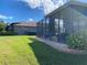 A view of the backyard featuring a screened-in patio and a green lawn at 585 Meandering Way, Polk City, FL 33868