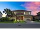 Stunning two-story home with a tile roof, arched entryway, and manicured landscaping at dusk at 6160 Broad Oak Dr, Davenport, FL 33837