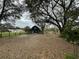 Exterior view of barn with fenced yard and mature trees, creating a serene rural setting at 6615 Broken Arrow S Trl, Lakeland, FL 33813