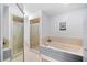 Bright bathroom featuring a tub, a glass-enclosed shower, and neutral-toned tile at 6615 Broken Arrow S Trl, Lakeland, FL 33813