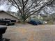 Exterior view of the home and parking area with a large tree and multiple vehicles parked at 6615 Broken Arrow S Trl, Lakeland, FL 33813