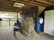 Indoor horse stall with hay, lawn equipment, and other supplies, perfect for equestrian enthusiasts at 6615 Broken Arrow S Trl, Lakeland, FL 33813