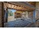 View of the inside of a horse stall with a hay-covered floor, wood-beam construction, and a gated entrance at 6615 Broken Arrow S Trl, Lakeland, FL 33813