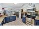 Well-lit kitchen featuring granite counters, stainless steel appliances, and blue lower cabinets at 6615 Broken Arrow S Trl, Lakeland, FL 33813