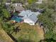 Aerial view showcases a backyard with screened-in pool and playset next to a home and large lawn at 7410 Locksley Ln, Lakeland, FL 33809