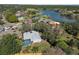 Aerial view showcases a house with a screened-in pool, lush landscaping, and nearby lake at 7410 Locksley Ln, Lakeland, FL 33809