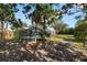 Lush backyard with mature trees, screened pool enclosure, playset, and view of the home's exterior at 7410 Locksley Ln, Lakeland, FL 33809