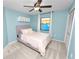 Light blue bedroom with a ceiling fan, large window, and a gray upholstered bedframe at 7410 Locksley Ln, Lakeland, FL 33809