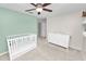 Cozy bedroom featuring a white crib, dresser, neutral carpet, and a modern ceiling fan at 7410 Locksley Ln, Lakeland, FL 33809