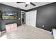 Gray bedroom features a ceiling fan, gray walls, television, open closet doors and small pink shelf at 7410 Locksley Ln, Lakeland, FL 33809