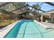 Relaxing screened pool area with lush landscaping, porch swing, and an outdoor grill for summer enjoyment at 7410 Locksley Ln, Lakeland, FL 33809