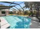 A screen-enclosed pool with a playset and tropical landscaping creates a backyard oasis for summer fun at 7410 Locksley Ln, Lakeland, FL 33809