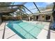 Wide view of the clear blue pool, screened-in porch, patio, and lush landscaping, perfect for relaxation at 7410 Locksley Ln, Lakeland, FL 33809