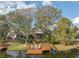 Aerial view of property boasting a lakeside dock with seating and swing, surrounded by lush trees and serene water at 794 Lake Clark Ct, Lakeland, FL 33813