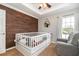 Bedroom bedroom with white crib, wooden accent wall, carpeted floors, and natural light at 794 Lake Clark Ct, Lakeland, FL 33813