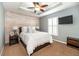 Comfortable bedroom features a wood accent wall, tray ceiling with fan, and a mounted TV at 794 Lake Clark Ct, Lakeland, FL 33813