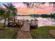 Waterfront backyard featuring a private wooden dock with seating on a serene lake at sunset at 794 Lake Clark Ct, Lakeland, FL 33813