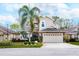 Charming two-story home featuring a well-manicured lawn, two-car garage, stone accents, and a lush palm tree at 794 Lake Clark Ct, Lakeland, FL 33813