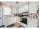 Kitchen area features white cabinetry, laminate floors, a range oven, and double basin sink at 144 Mirror Nw Ln, Winter Haven, FL 33881