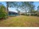 Large backyard with trees, grassy lawn, and a view of the back of the house with a screened-in porch at 15 Tera Ln, Winter Haven, FL 33880