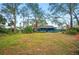 Scenic view of a large backyard with mature trees, well-kept lawn, and the home's screened porch visible at 15 Tera Ln, Winter Haven, FL 33880