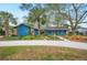 Charming single Gathering home with a long drive and a front yard featuring mature landscaping and a vibrant blue facade at 15 Tera Ln, Winter Haven, FL 33880