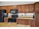 Close up of the kitchen featuring wood cabinets, granite countertops, and black appliances at 15 Tera Ln, Winter Haven, FL 33880