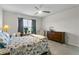 Sunlit bedroom with a wooden dresser, ceiling fan, and large window at 2027 Airedale Way, Lake Alfred, FL 33850